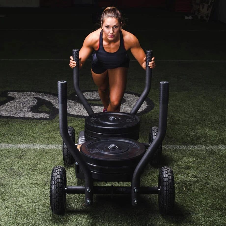 Atleta empujando un trineo Torque Tank cargado con discos